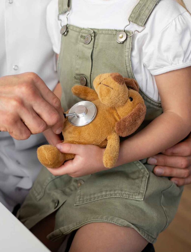 Ein Arzt hört den Teddy eines Kindes ab