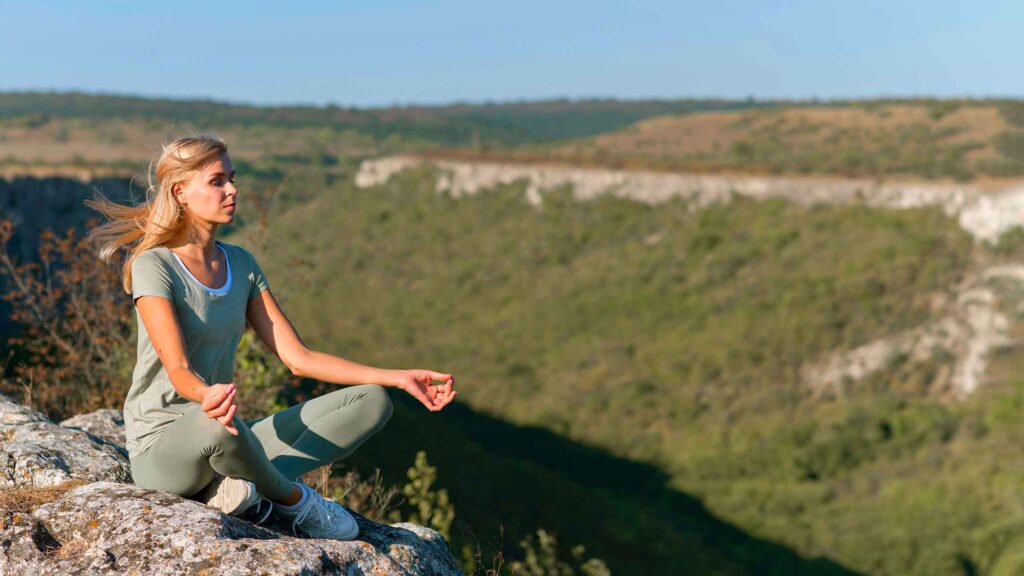 Eine Frau in Yoga-Pose auf einem Felsen