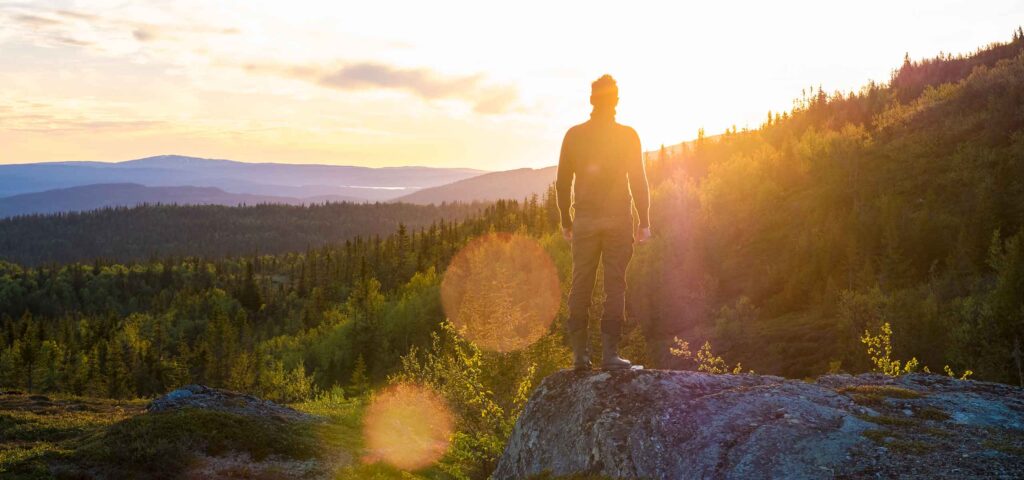 Ein Mann schaut sinnierend über eine wunderschöne Landschaft